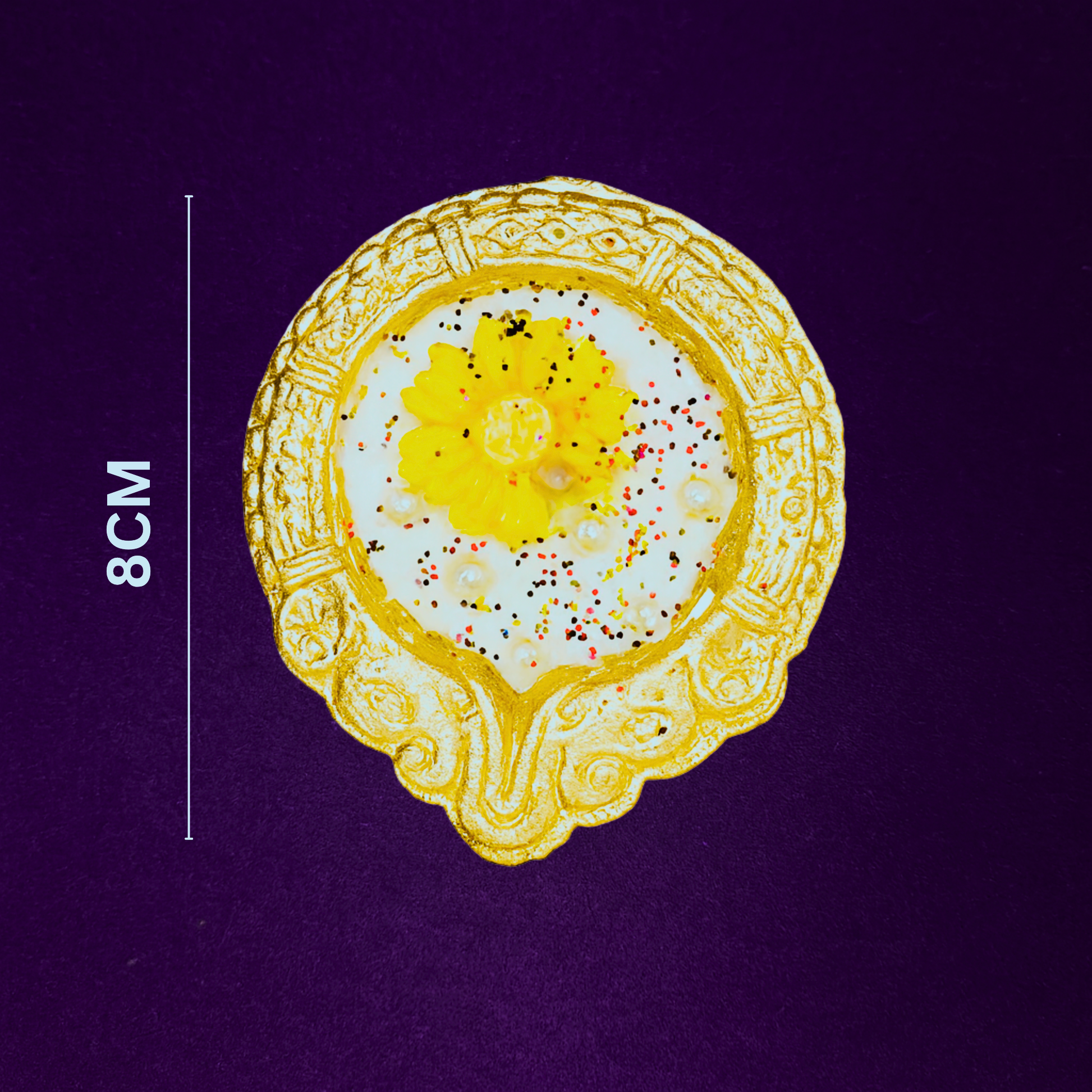 Amber Bloom Diya Candle by Karigar Kutir — 8 cm handcrafted soy wax fragrant candle in an ornate golden holder with yellow marigold design, displayed on a purple background for size reference and festive detailing.