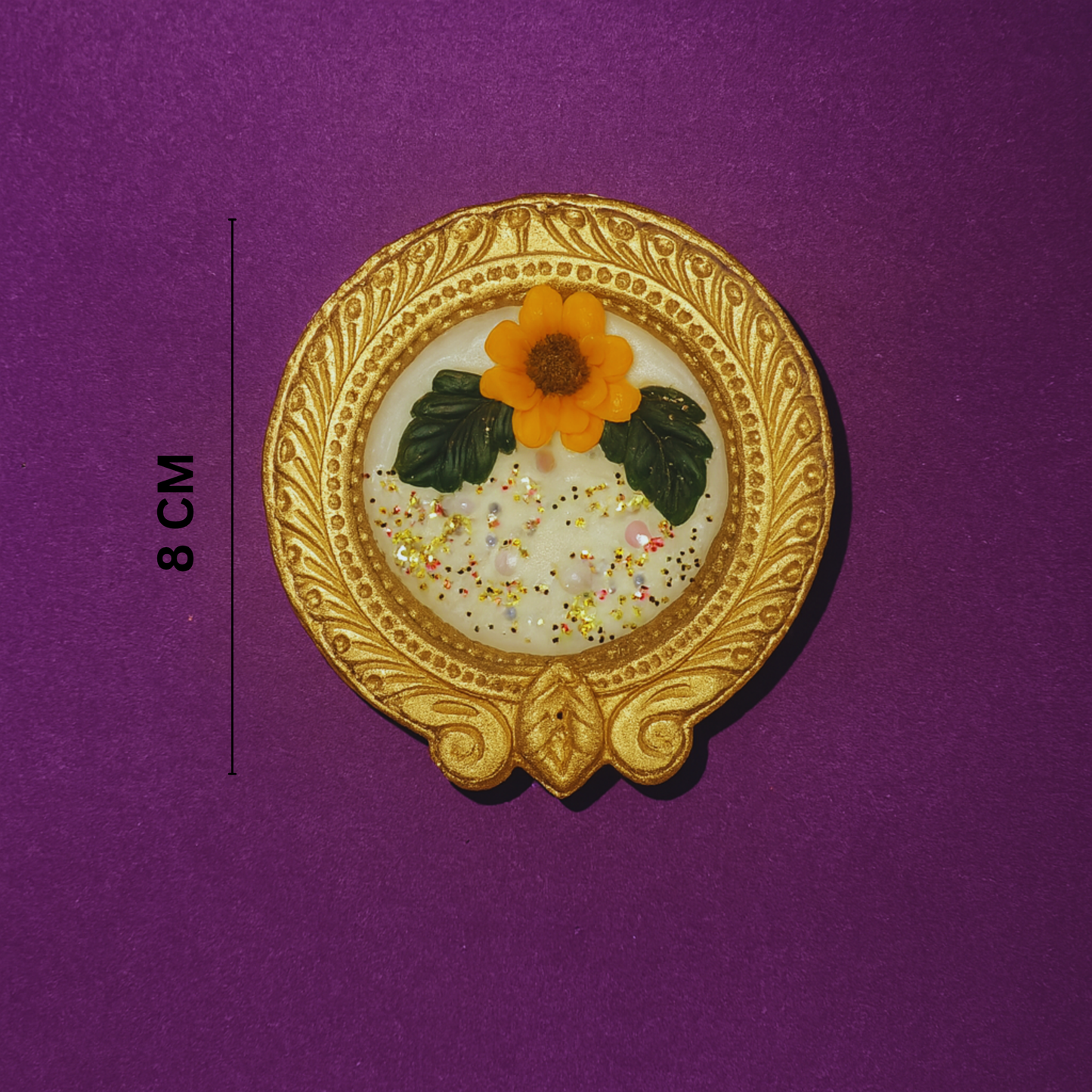Golden Radiance Diya Fragrant Candle by Karigar Kutir — 8 cm handcrafted soy wax candle in ornate golden holder with marigold flower design, showcased on a purple background for size reference and product detailing.
