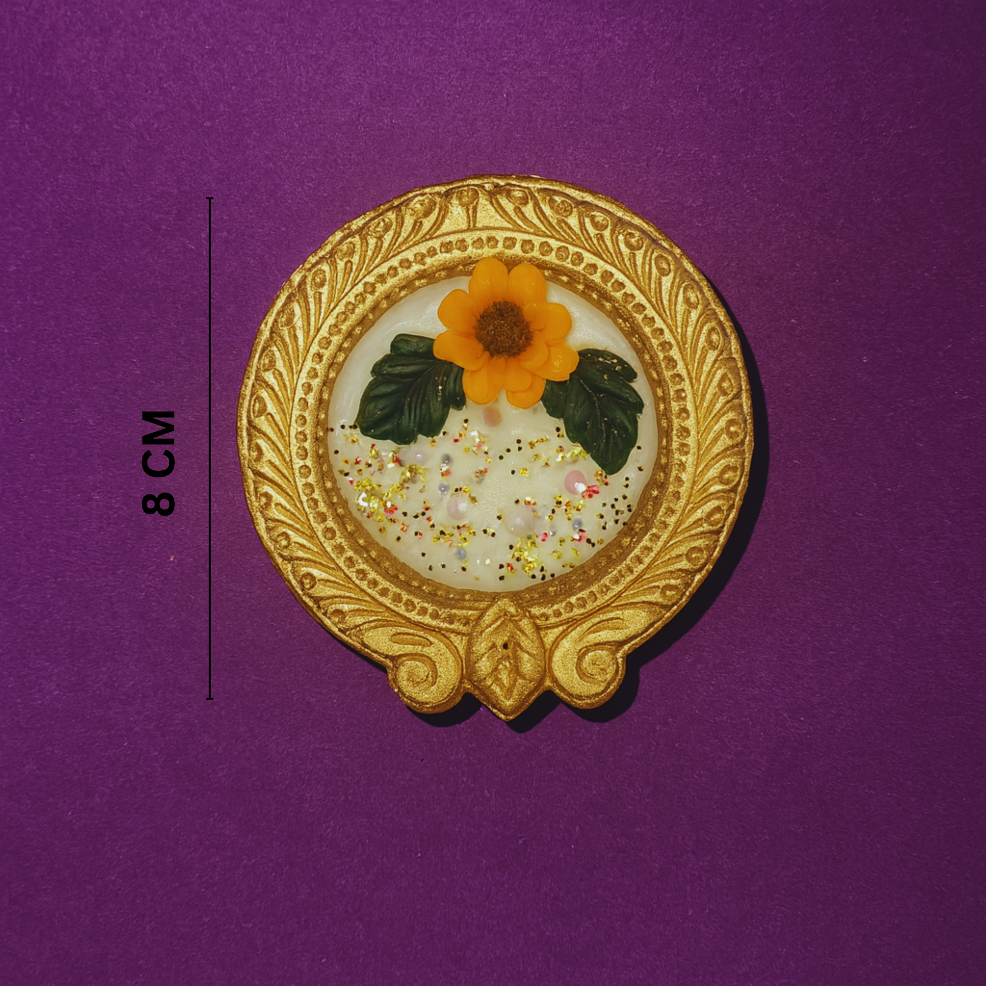 Golden Radiance Diya Fragrant Candle by Karigar Kutir — 8 cm handcrafted soy wax candle in ornate golden holder with marigold flower design, showcased on a purple background for size reference and product detailing.