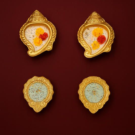 Golden Shankh Aura Set by Karigar Kutir — set of four handcrafted soy wax fragrant candles in ornate golden shankh and diya-shaped holders, decorated with red and yellow floral accents on a deep maroon background for Diwali décor and gifting.