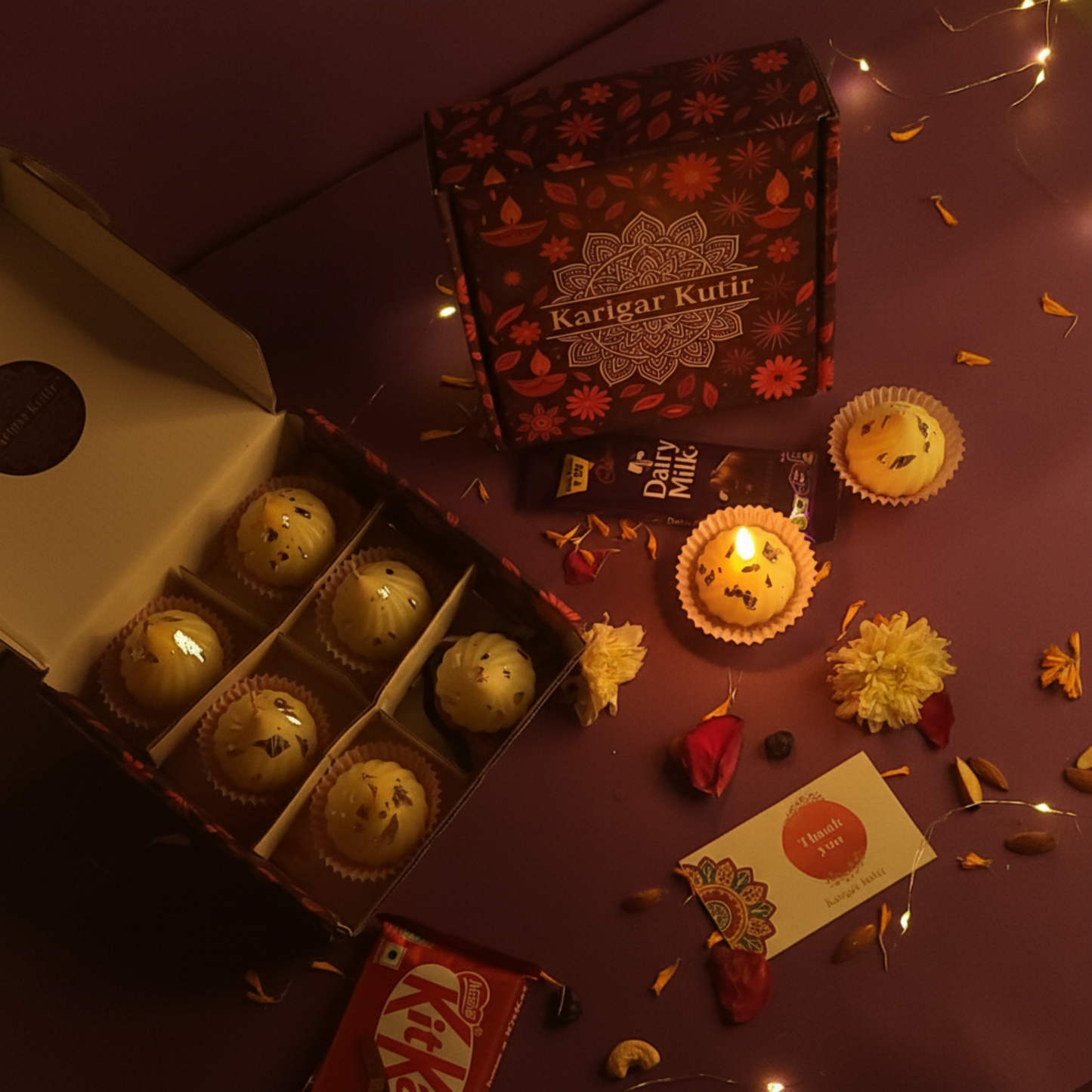 Karigar Kutir festive gift box featuring handmade Modak-shaped candles, chocolates, and a thank-you card, styled with marigold petals, fairy lights, and warm festive lighting — perfect for Diwali gifting and traditional celebration.
