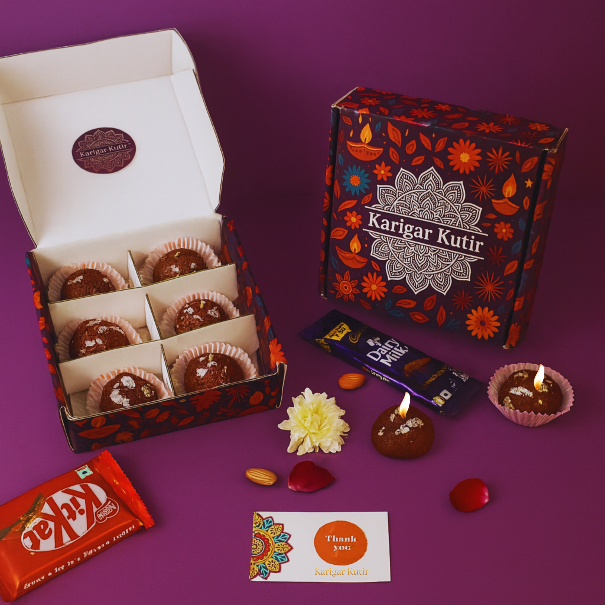 Karigar Kutir festive gift box featuring handmade Gulab Jamun-shaped candles with silver varq detailing, paired with chocolates, a thank-you card, and decorative petals — captured in warm festive lighting for Diwali gifting.