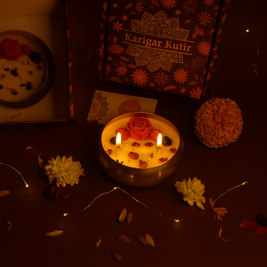 Decorative candle with flowers and a 'Karigar Kutir' box in a warm, dimly lit setting.